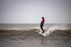 A longboarder soul arches across a wave, perfectly surfing their longboard in a hang ten