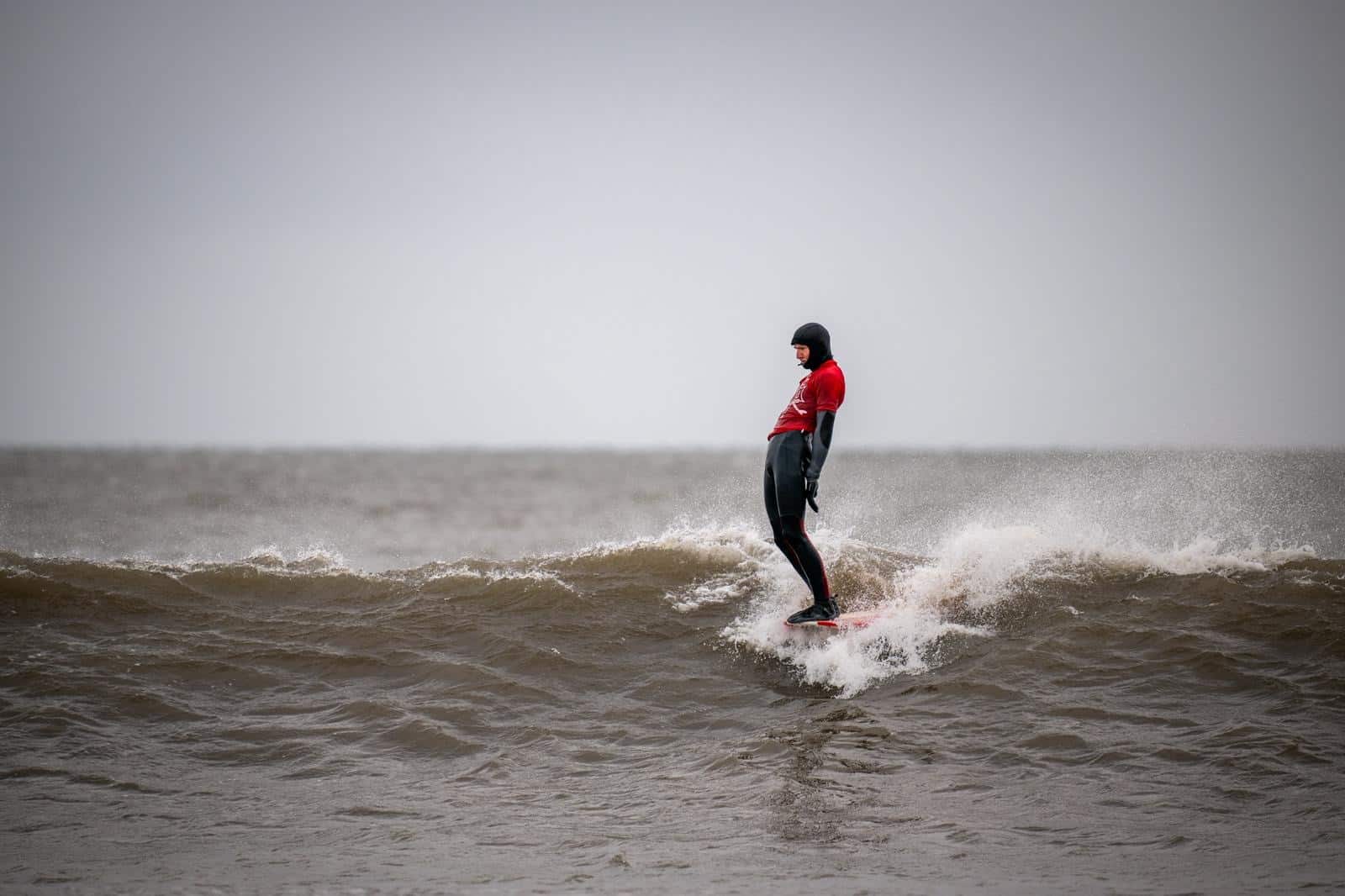 A longboarder soul arches across a wave, perfectly surfing their longboard in a hang ten